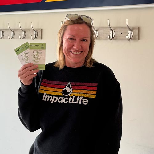 woman wearing impactlife sweatshirt holding two tickets
