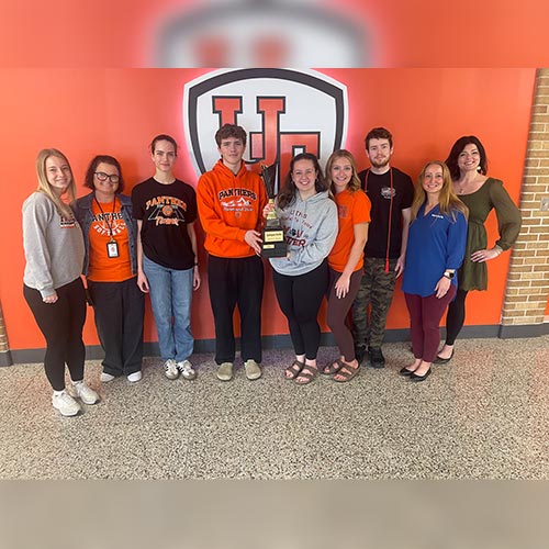 Group of people smiling holding trophy as winners of QC battle for blood