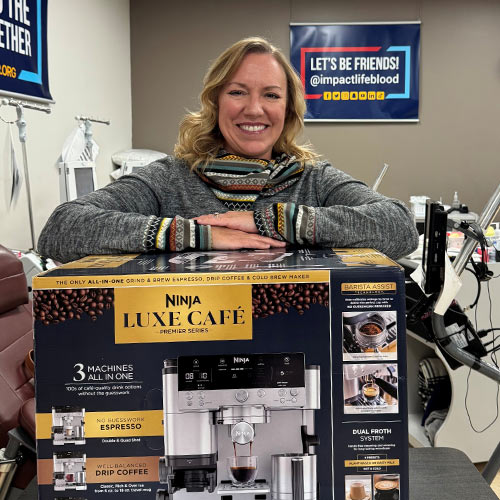 woman holding box labeled Ninja Luxe Cafe standing in impactlife donor center