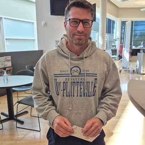 Man in gray sweatshirt holding tickets
