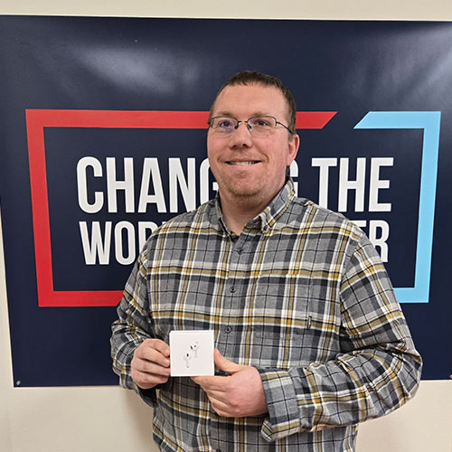 Man with glasses and plaid shirt holding airpods 4 box at ImpactLife