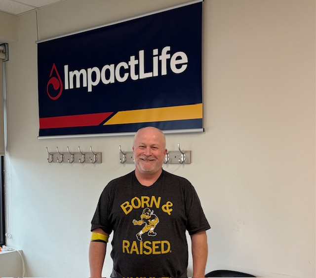 Man standing in front of ImpactLife sign