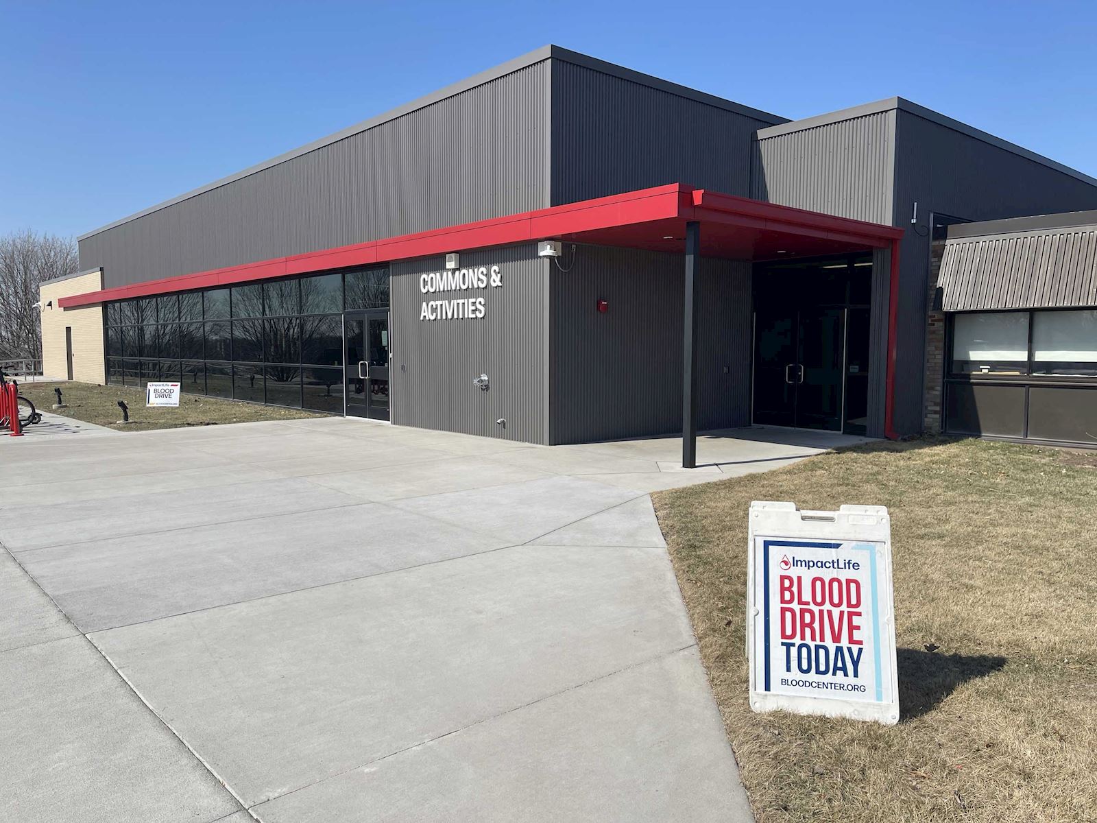 Outside view of the Commons & Activities building with an ImpactLife Blood Drive sign out front.