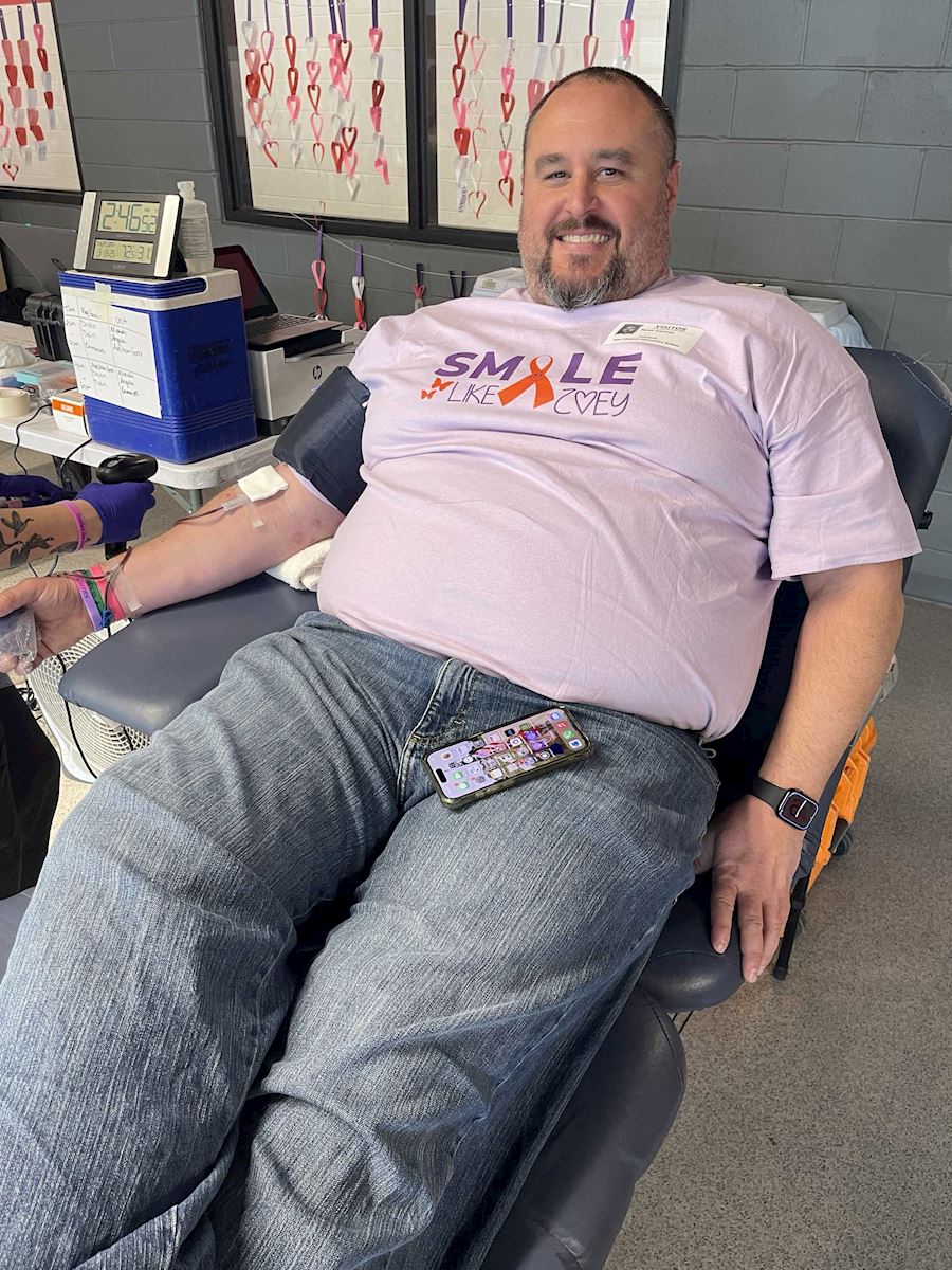 Man wearing a 'Smile Like Zoey' shirt while donating blood at the ImpactLife drive.