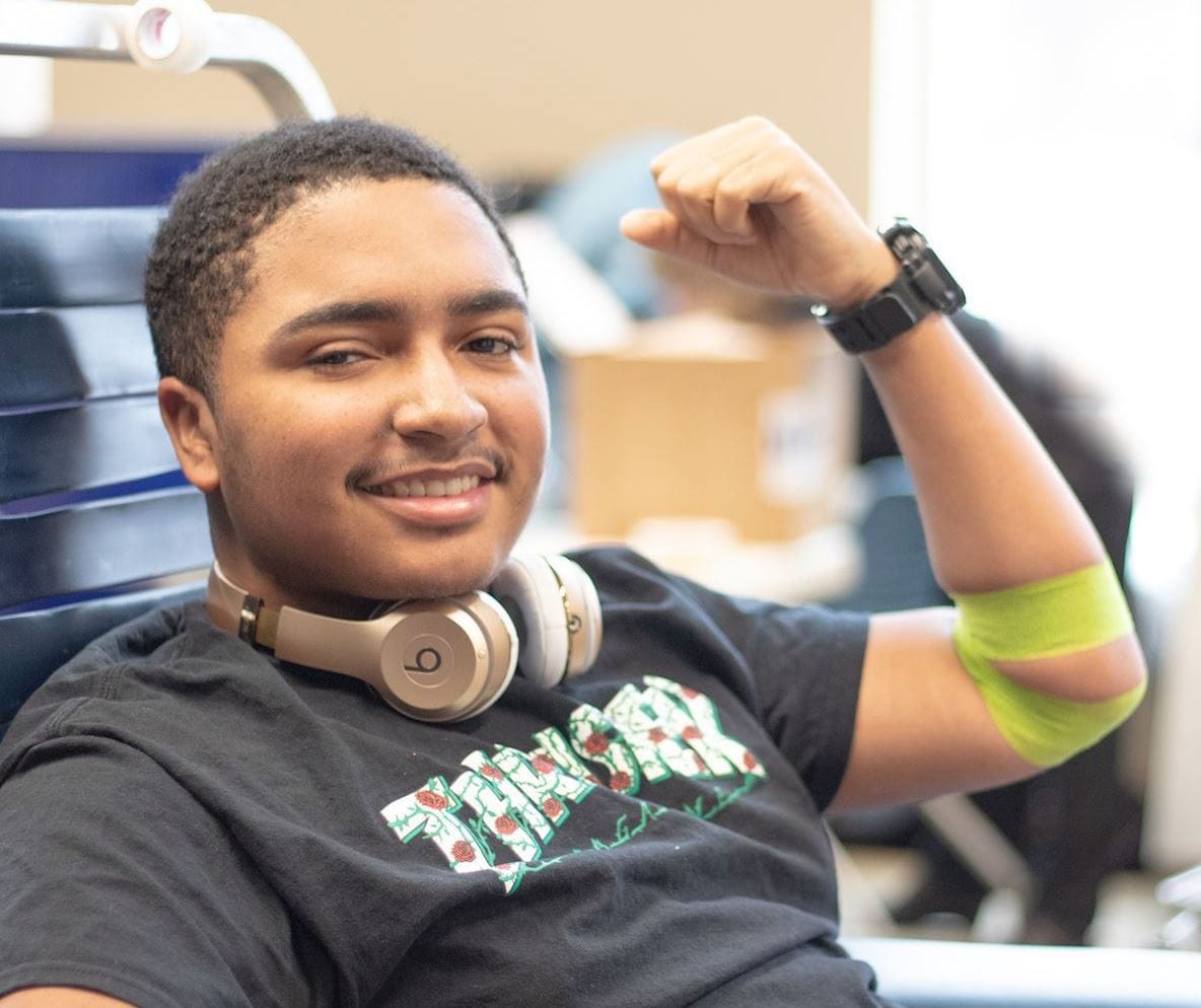 smiling male blood donor flexing arm with green coflex after donating