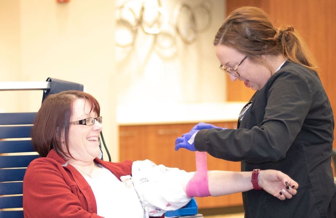 female blood donor and female phlebotomist at blood drive